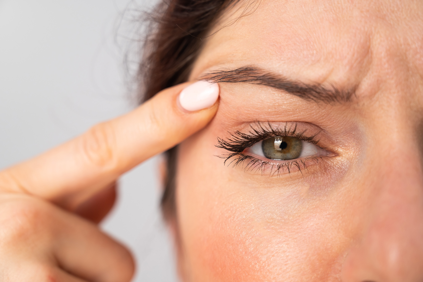 Close-up image of a client's face, highlighting the eye area with long lashes and flawless skin. A hand delicately touches the eyebrow, reflecting the elegant results achievable through Botox and other non-surgical cosmetic procedures at our luxury medical spa near Philadelphia in King of Prussia, PA.