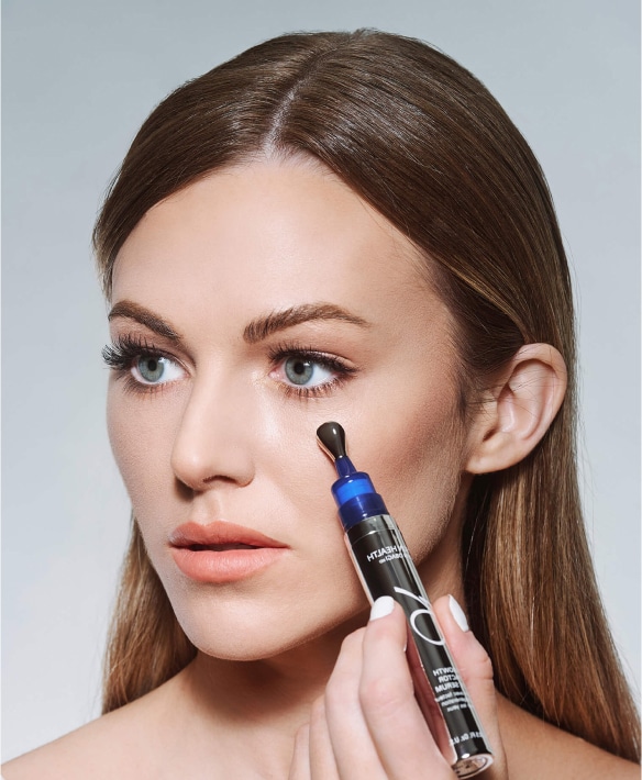 Brunette client applying ZO® Growth Factor Eye Serum, reflecting targeted skincare available at Allure Aesthetics for clients in King of Prussia, the Main Line, and Philadelphia