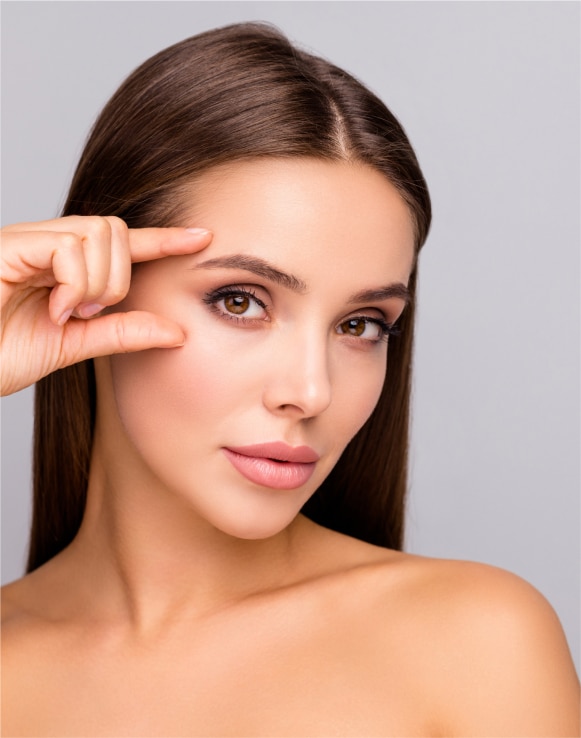 Brunette woman touching her eye area, representing Upneeq prescription eyelid-lifting drops offered at Allure Aesthetics in King of Prussia, near Philadelphia and the Main Line