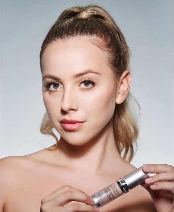 Blonde client holding Oxygenetix foundation, a breathable formula ideal for sensitive or post-procedure skin