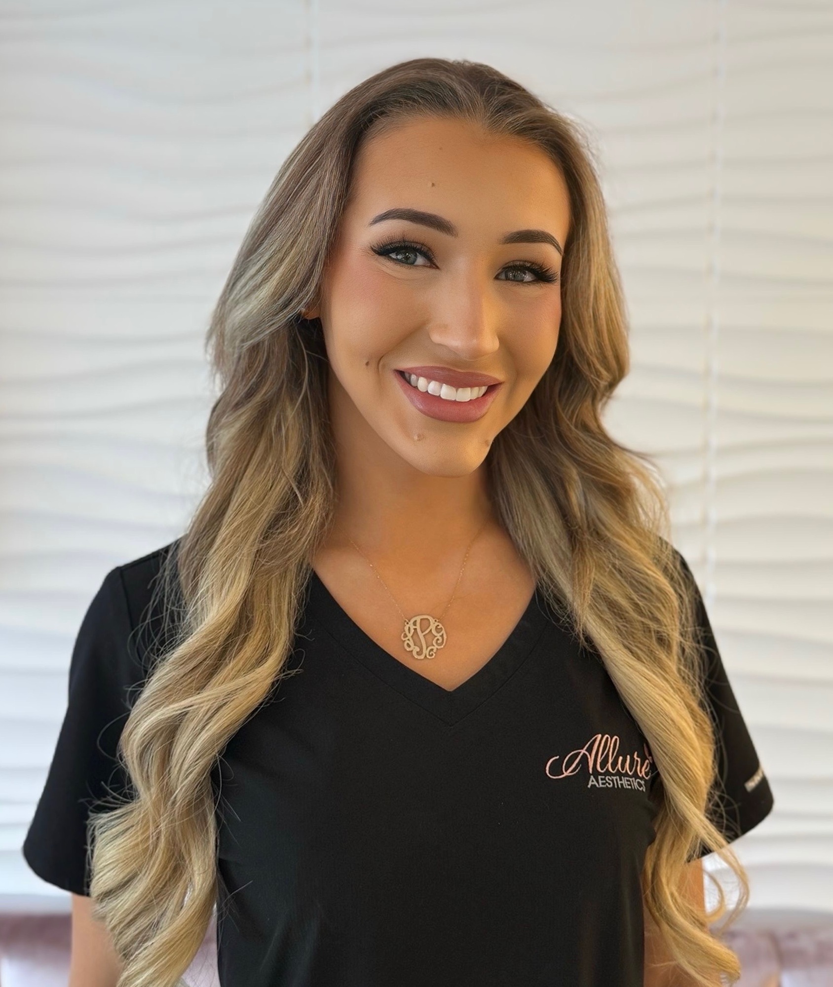 Lauren Powell, Medical Assistant at Allure Aesthetics, offering a kind, welcoming smile in a serene clinical setting.