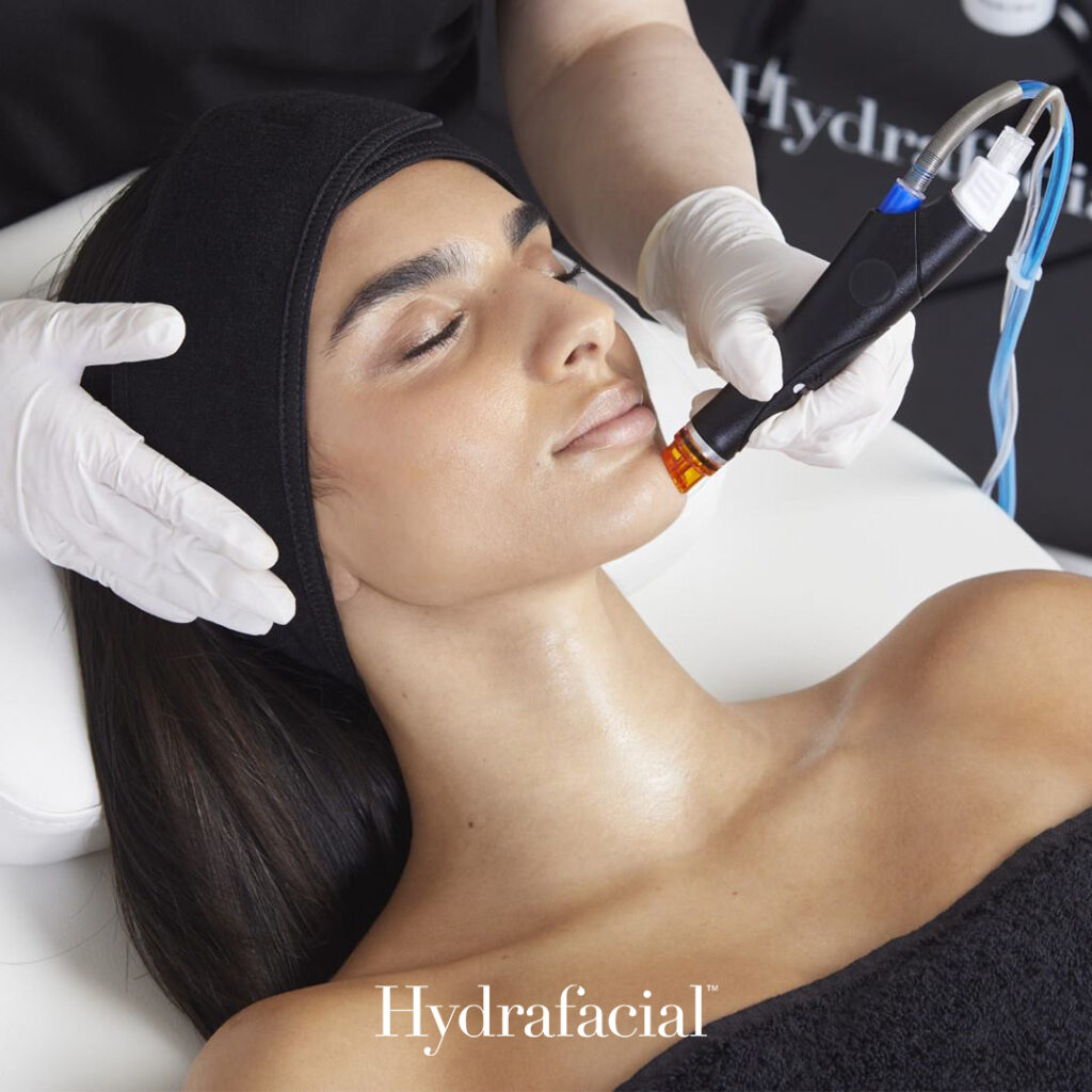 Woman lying on a treatment chair receiving a Hydrafacial procedure using a vortex-fusion handpiece