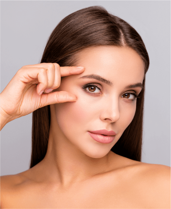 Brunette woman gently touching her temple, evoking lifted, refreshed eyes—symbolic of Latisse and Upneeq results